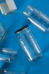 Glass jars with lids on blue background, top view flat lay recycling concept