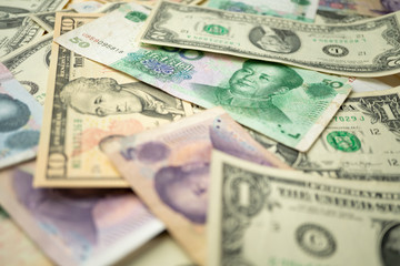 US dollar stack and Chinese yuan banknotes on the table The concept of a trade war between the United States and China
