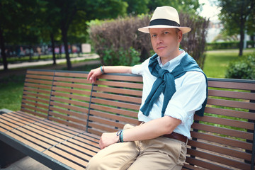 Fototapeta premium Portrait of a guy sitting on a park bench 