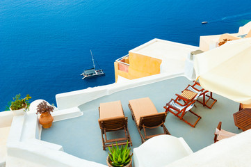 Chaise lounges on the terrace with sea view. Santorini island, Greece. Travel and vacation concept