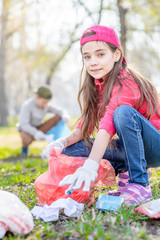 Young girl scavenge trash in the park. Volunteer and ecology concept