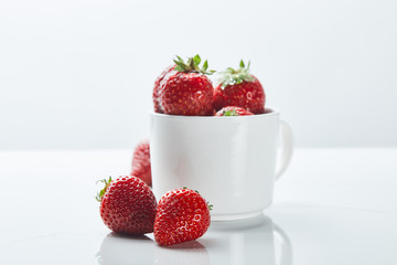 ripe sweet strawberries in cup on white background