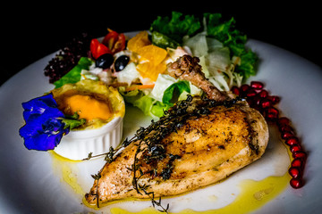 french chicken supreme grilled chicken with potato gratin and fruit salsa and pomegranate seeds and butterfly pea leaf