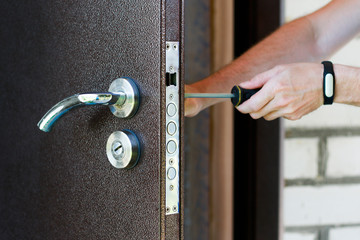 Handyman repair the door lock in metal entrance door, Man fixing lock with screwdriver, Close-up of repairing door, professional locksmith installing new deadbolt lock on house