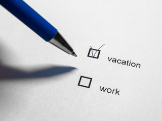 Vacation or work - tick on white paper with pen. The concept of choosing an office worker.