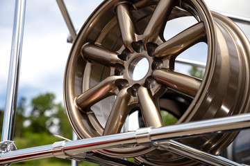 Modern metal alloy wheel for cars. Showcase with bronze colored rims. Closeup side and front view.