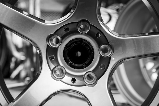 Modern metal alloy wheel for cars. Showcase with rims. Closeup side and front view. Black and white photo.