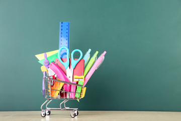 School supplies with shopping cart on chalkboard background