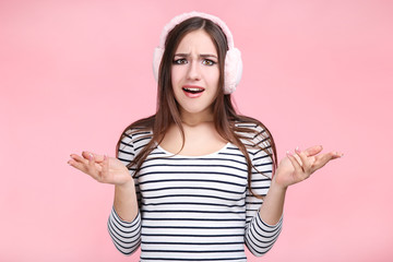 Beautiful young woman with warm headphones on pink background