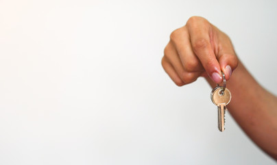 close up young asian man hand holding house's key on white background with copyspace for design of home loan concept