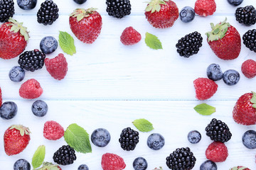 Ripe and sweet fruits with green leafs on white wooden table