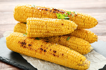 Grilled corn with green parsley on wooden table