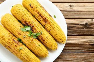 Grilled corn with green parsley on brown wooden table
