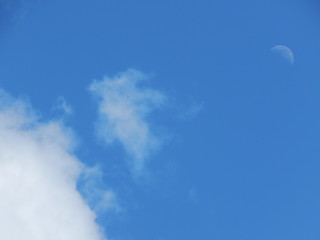 Hintergrund mit weißen Wolken und Mond am blauen Tageshimmel, Raum für Text
