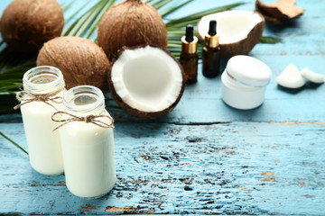 Coconut milk in bottles with fruit and palm leafs on blue wooden table