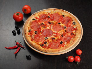 Pizza with salami, tomatoes and olives on a plate