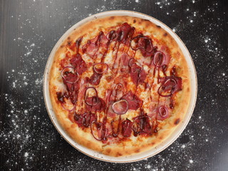 Pizza with ham, onions and cheese on a plate