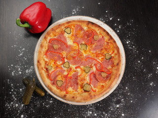 Pizza with sausage, pepper and pickled cucumbers on a plate