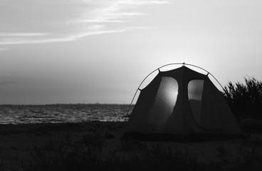 Camping tent on sea beach at sunset in summer