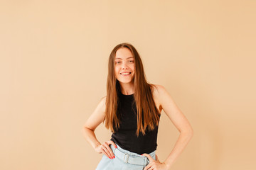 Obraz premium Cheerful attractive model in casual clothes standing with hands on waist on light background and looking at camera