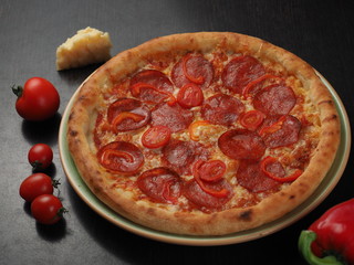 Pizza with salami, tomatoes and cheese on a plate