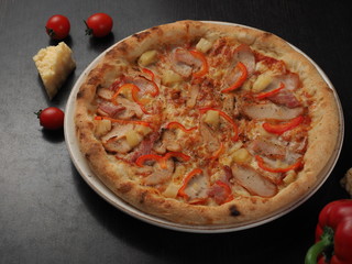 Pizza with ham, chicken, pepper and cheese on a plate
