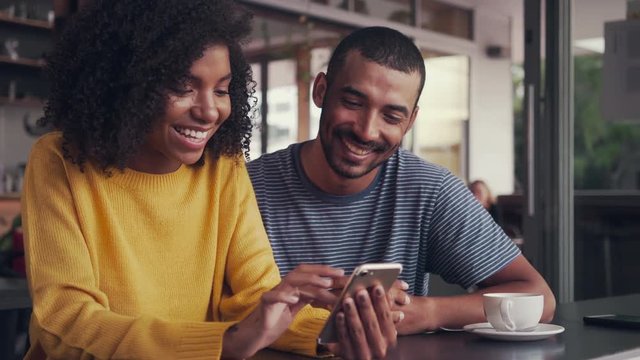 Woman sitting in cafe shares text with her friend