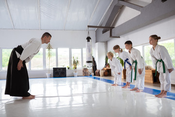 Fototapeta premium Trainer and pupils greeting each other before martial arts