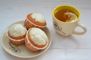 Cupcakes with cup of tea, light shabby background.