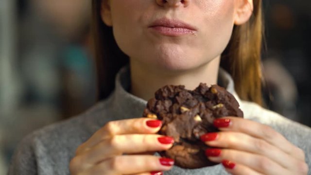 Woman eats a chocolate chip cookies in a cafe