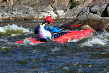Whitewater kayaking on fast moving water of mountain river among the rapids, extreme water sport. Kayak freestyle on whitewater. Man in red kayak