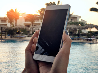 Young woman using cellphone near the swimming pool.