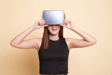 Young Asian woman with a computer tablet over her face.