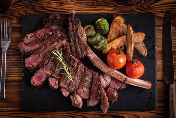 grilled tomahawk ribeye steak on black stone plate