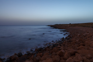 Fototapeta na wymiar Night sascape. Natural rocks on the shore, salty water and long exposure. Cyprus, Mediterranean sea.