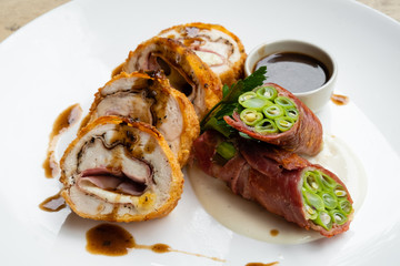 close up of stuffed pork cutlet with ham, cheese and vegetable isolated on a white plate