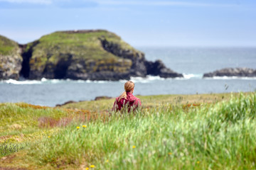Girl walking in field near Atlantic Ocean in Newfoundland