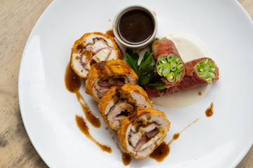 close up of stuffed pork cutlet with ham, cheese and vegetable isolated on a white plate