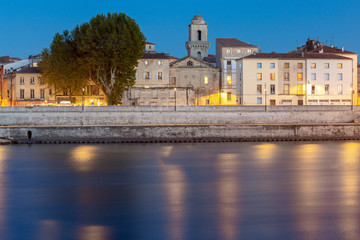 Arles. City embankment and facades of old houses at sunset.