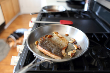 Steelhead trout frying in a pan with the skin side up.