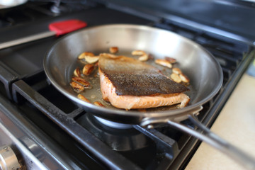 Steelhead trout frying in a pan with the skin side up.