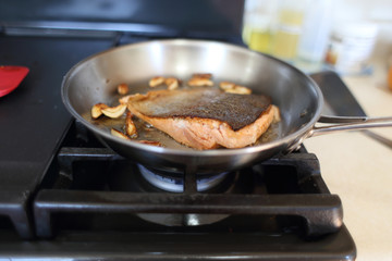 Steelhead trout frying in a pan with the skin side up.