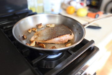 Steelhead trout frying in a pan with the skin side up.
