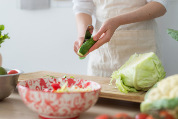 Cooking salad from fresh vegetables. Woman cuts vegetables on a cutting board.