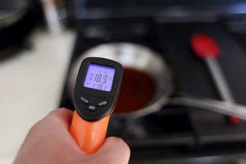 Using a laser temperature gun to check the heat level of a skillet on the stove top.