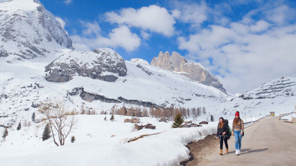 Fototapeta na wymiar Two young women tourist traveling on the road in Dolomites with big backpack and guitar