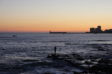 Pêcheur sur les roches noires des Sables d'Olonne au coucher de soleil