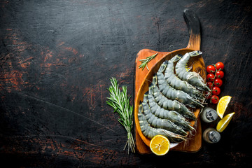 Raw shrimps with lemon slices, rosemary and tomatoes.