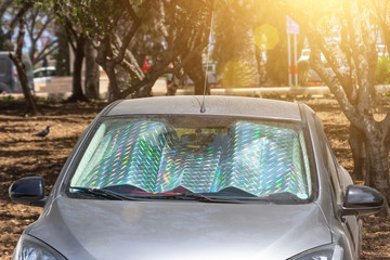 Protective reflective surface under the windshield of the passenger car parked on a hot day, heated...