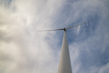 One wind turbine with cloudy sky in background